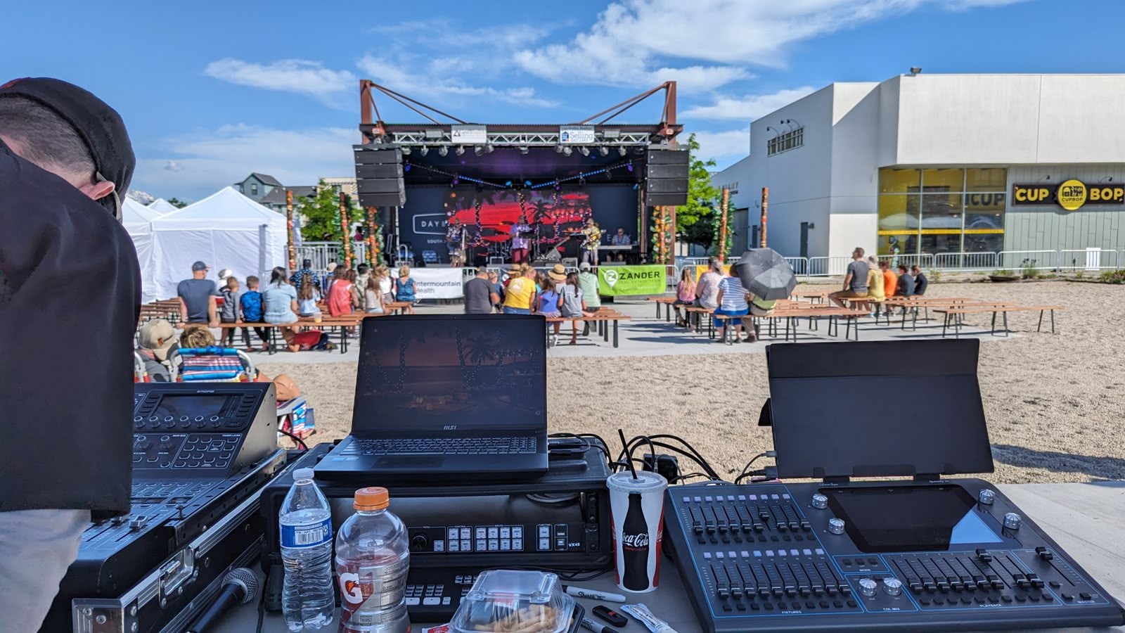An outdoor front-of-house console and line-array PA at a concert
