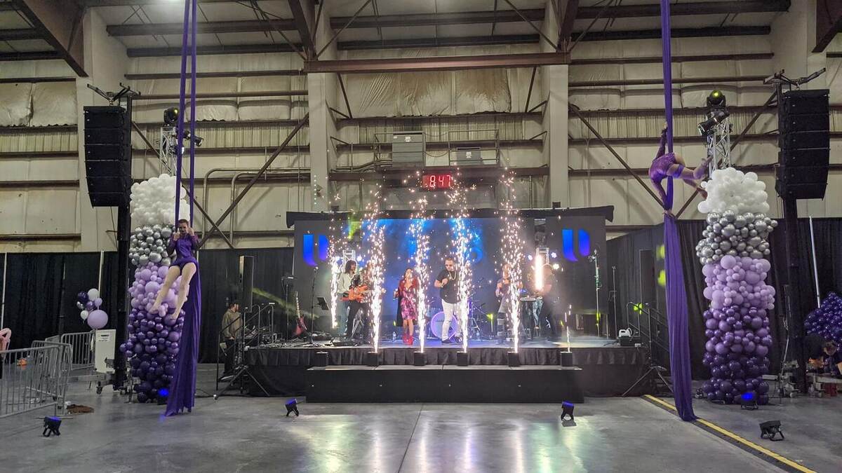The 'udo' stage during a pyro moment with sparkler fountains firing, band performing, LED wall lit, and balloon-and-silk decor flanking