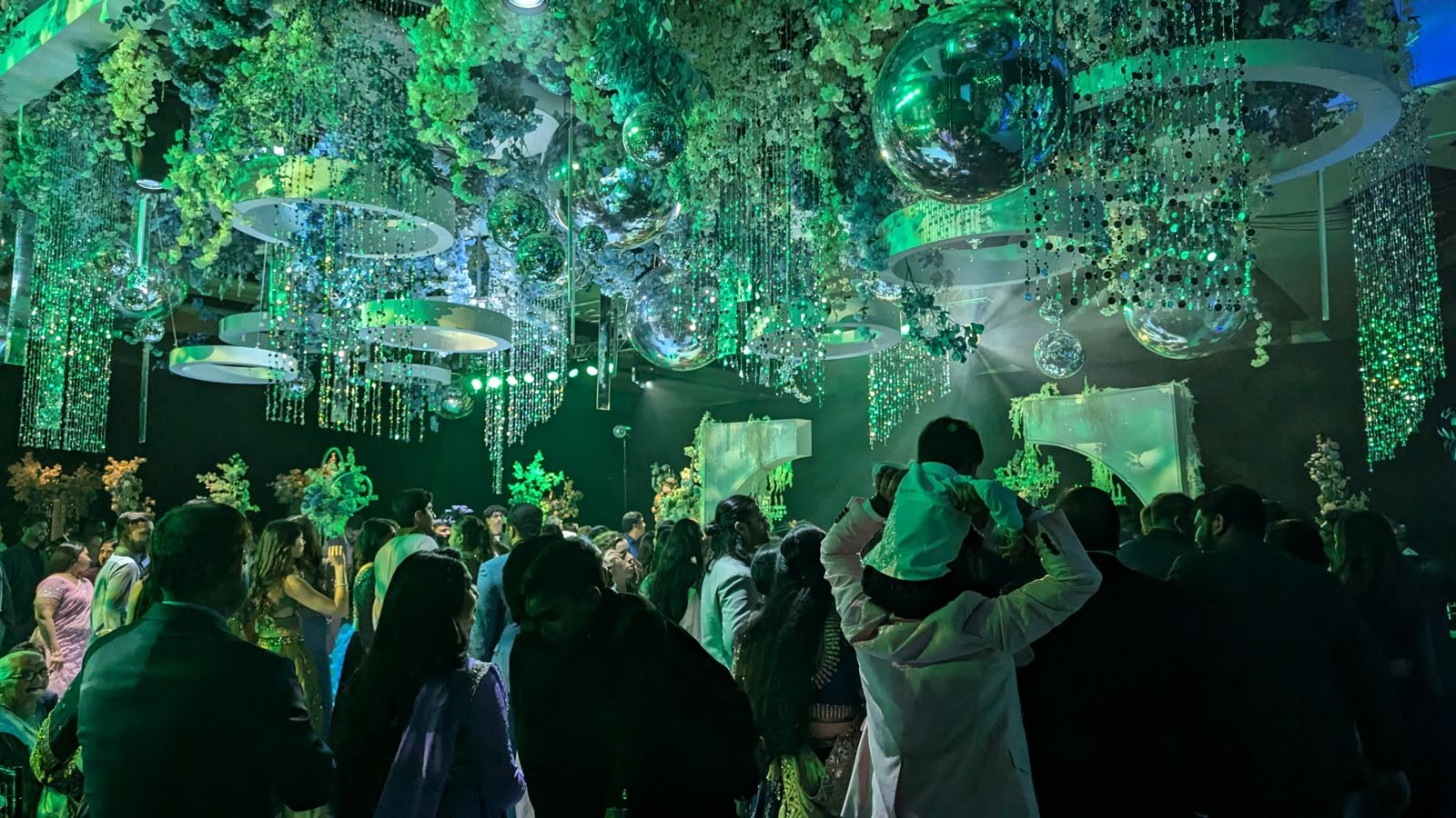 A packed dance floor under green concert lighting