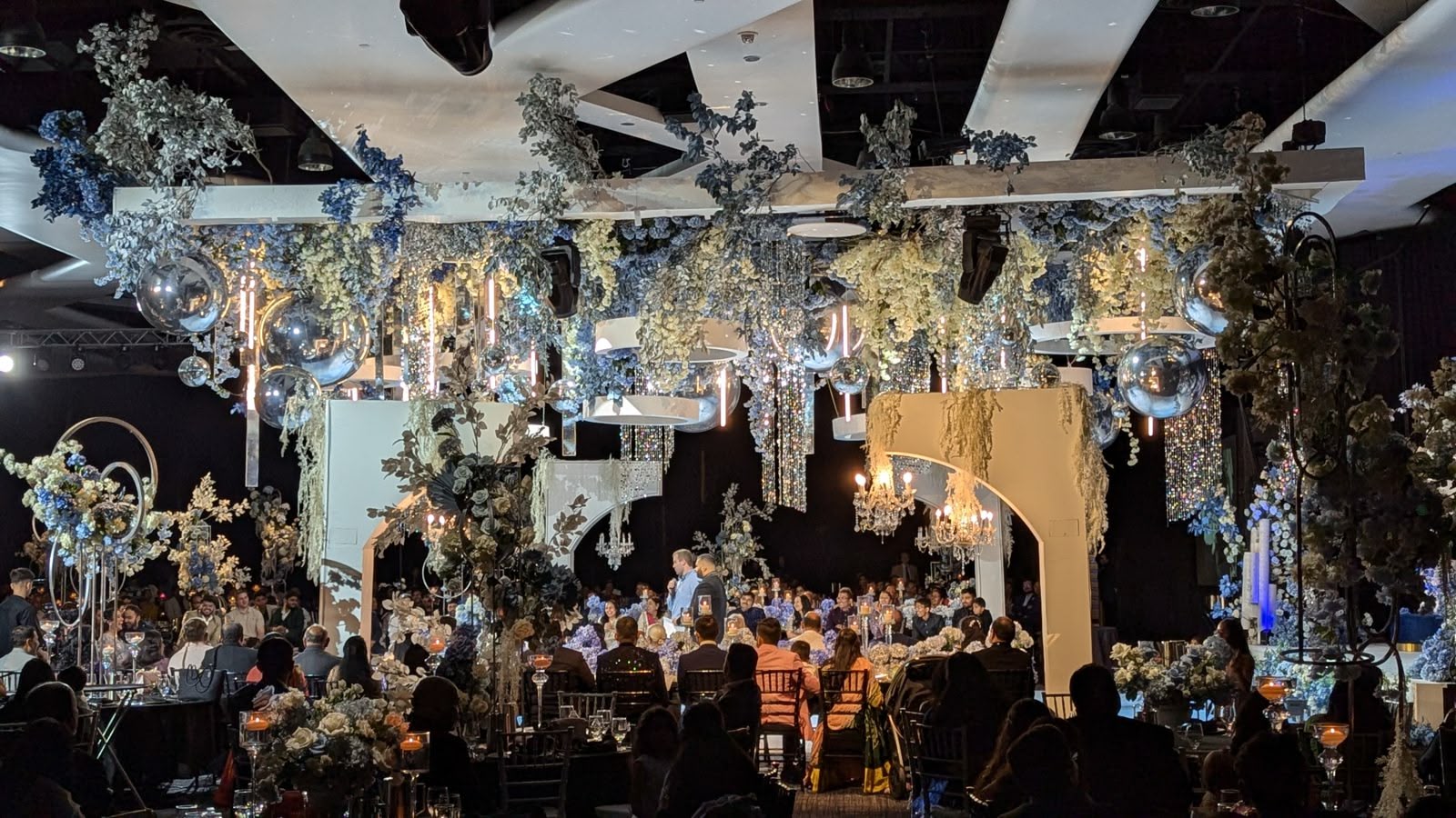 A grand ballroom transformed with blue and white floral and full lighting
